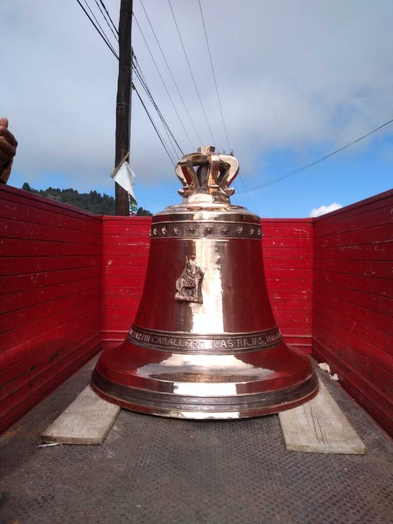 Campana de bronce grande en la parte trasera de un camión rojo.